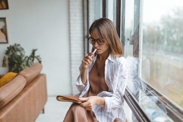 Mulher sentado perto de uma janela fechada. Tomada de decisões com o tarô.