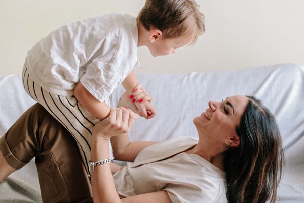 Mulher brincando com o filho no sofá.