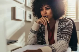 Avaliando alternativas com o tarô. Mulher negra sentada em frente ao computador, analisando.